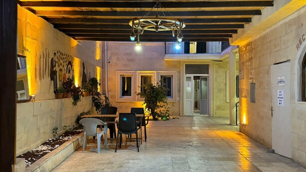 A courtyard with a covered seating area, potted plants, and a mural on the wall. - Arton In Cappadocia (Avanos)
