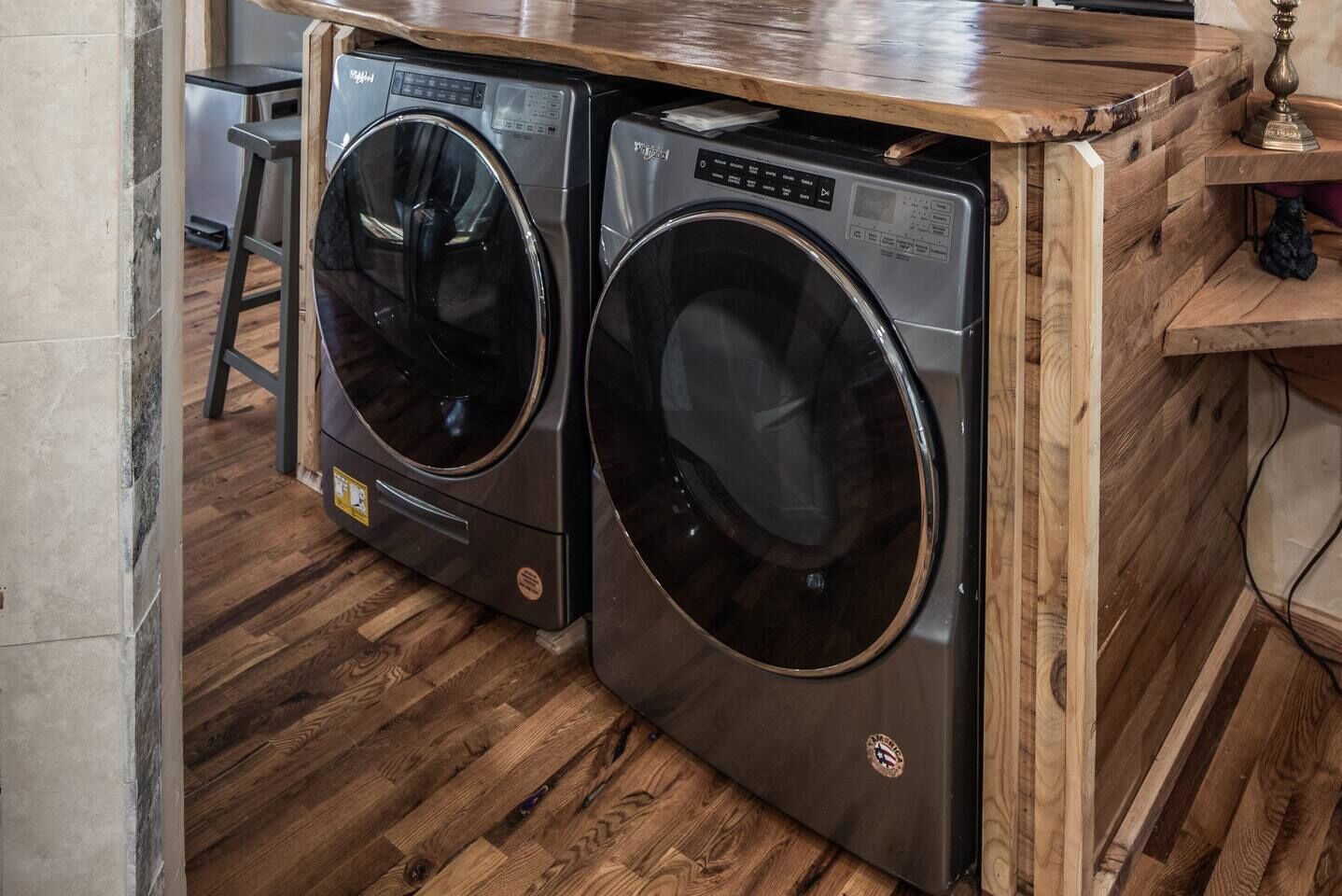 A compact laundry area with two front-loading washing machines and a wooden countertop.