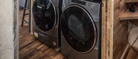A compact laundry area with two front-loading washing machines and a wooden countertop.