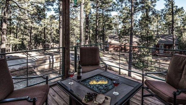 A deck with a fire pit table, two chairs, and a bottle of wine. - Redwood in the Historic Upper Canyon (Ruidoso)