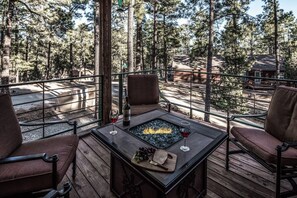 Eine Terrasse mit Feuerstelle, zwei Stühlen und einer Weinflasche.