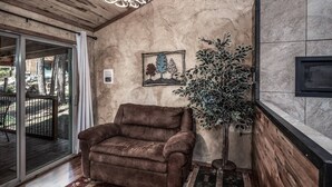 A cozy room with a brown leather sofa, a large potted plant, and a framed artwork on the wall. - SneakAway in the Historic UpperCanyon! (Ruidoso)