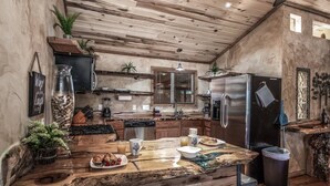 A rustic kitchen with a wooden island, stainless steel appliances, and a large window. - SneakAway in the Historic UpperCanyon! (Ruidoso)