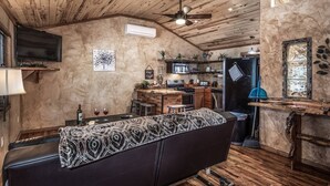 A cozy cabin interior with a wooden ceiling, a bar area, a sofa, and a television. - SneakAway in the Historic UpperCanyon! (Ruidoso)