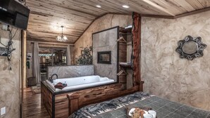 A bedroom with a large wooden bed, a bathtub, and a breakfast tray on the bed. - SneakAway in the Historic UpperCanyon! (Ruidoso)