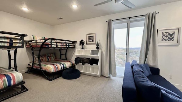A room with bunk beds, a sofa, a fan, a window with curtains, and a view. - The Lofts #44 | Townhome Pool Resort (Saint George)