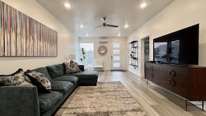 A modern living room with a sectional sofa, a flat-screen TV, and a ceiling fan. - The Lofts #44 | Townhome Pool Resort (Saint George)