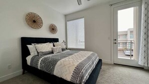 A bedroom with a bed, a window with blinds, and a door leading to a balcony. - The Lofts #44 | Townhome Pool Resort (Saint George)
