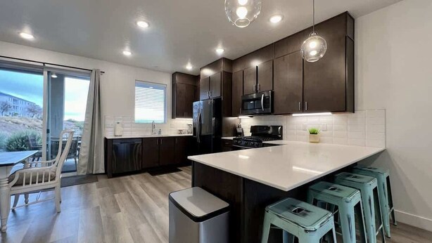 A modern kitchen with dark wood cabinets, a white countertop, and a black refrigerator.