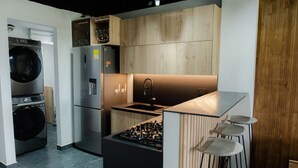A compact kitchen with a built-in washer and dryer, a stainless steel refrigerator, and a gas stove. - Apartment with lake access and jacuzzi in El Peñol, Antioquia (Peñol)