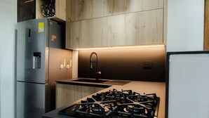 A modern kitchen with a stainless steel refrigerator, a built-in gas stove, and a wooden backsplash. - Apartment with lake access and jacuzzi in El Peñol, Antioquia (Peñol)