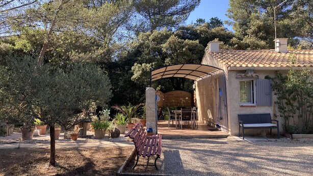 Eine rustikale Villa mit überdachter Terrasse, Gartenmöbeln im Freien und einem Garten mit Blumentöpfen.