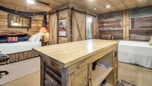 A room with two beds, a wooden desk, a ceiling fan, and a poster on the wall. - Casas Coastal Experience Cabin A (Rockport)