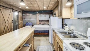 Une cuisine de taille réduite, dotée de meubles en bois, d’un réfrigérateur blanc, d’un four à micro-ondes, d’un évier et d’une cuisinière.
