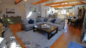 A living room with a sectional sofa, a coffee table, and a dining area with chairs and a table. - Updated 3 Bedroom Offering Hot Tub and Large Yard (2360) (Brewster)