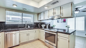 A modern kitchen with white cabinets, a stainless steel dishwasher, a built-in oven, and a black countertop. - 8 Mi to State Farm Stadium! Poolside Retreat (Peoria)