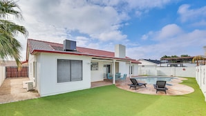 A modern house with a covered patio, a swimming pool, and a well-maintained lawn. - 8 Mi to State Farm Stadium! Poolside Retreat (Peoria)