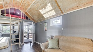 A room with a loft bed, a sofa, and a ladder. - Calabash Studio Cabin, 4 Mi to Sunset Beach! (Sunset Beach)