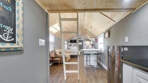 A loft-style room with a wooden ceiling, a ladder, a kitchenette, and a bed. - Calabash Studio Cabin, 4 Mi to Sunset Beach! (Sunset Beach)