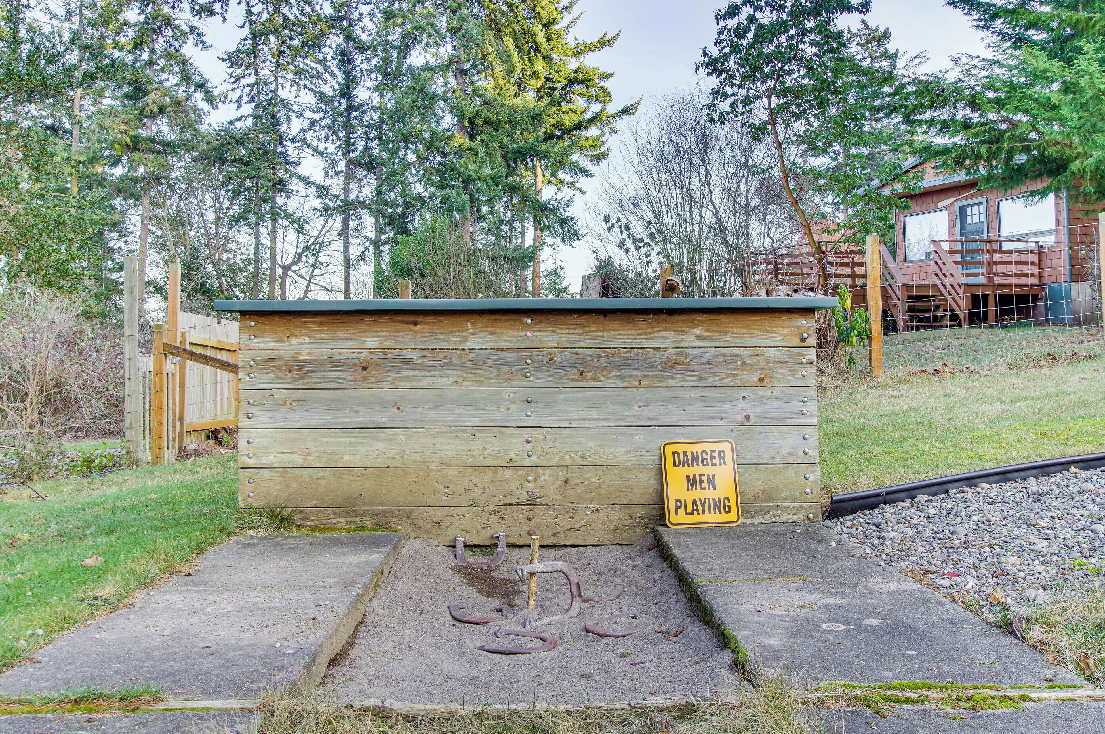 A wooden structure with a 'Danger Men Playing' sign, surrounded by trees and a gravel area.