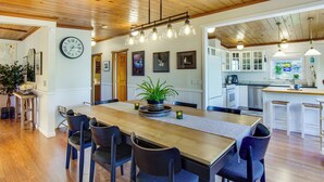 A spacious dining area with a wooden table, chairs, and a large clock on the wall. - Puget Sound Cottage w/ Private Community Beach! (Coupeville)