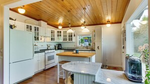 A kitchen with white cabinets, a wooden ceiling, and a marble countertop. - Puget Sound Cottage w/ Private Community Beach! (Coupeville)