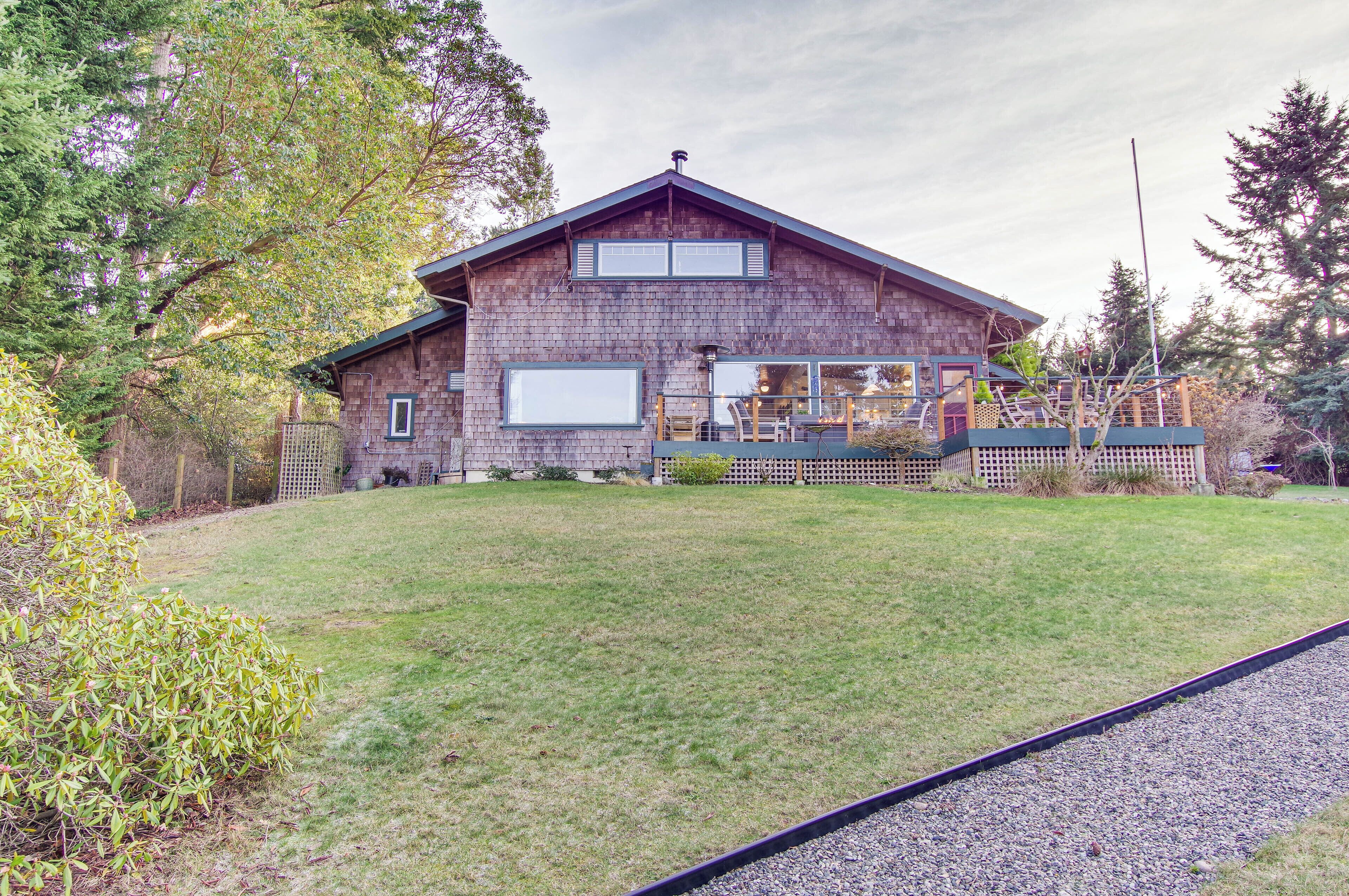 A rustic wooden house with a sloped roof, large windows, and a covered porch.