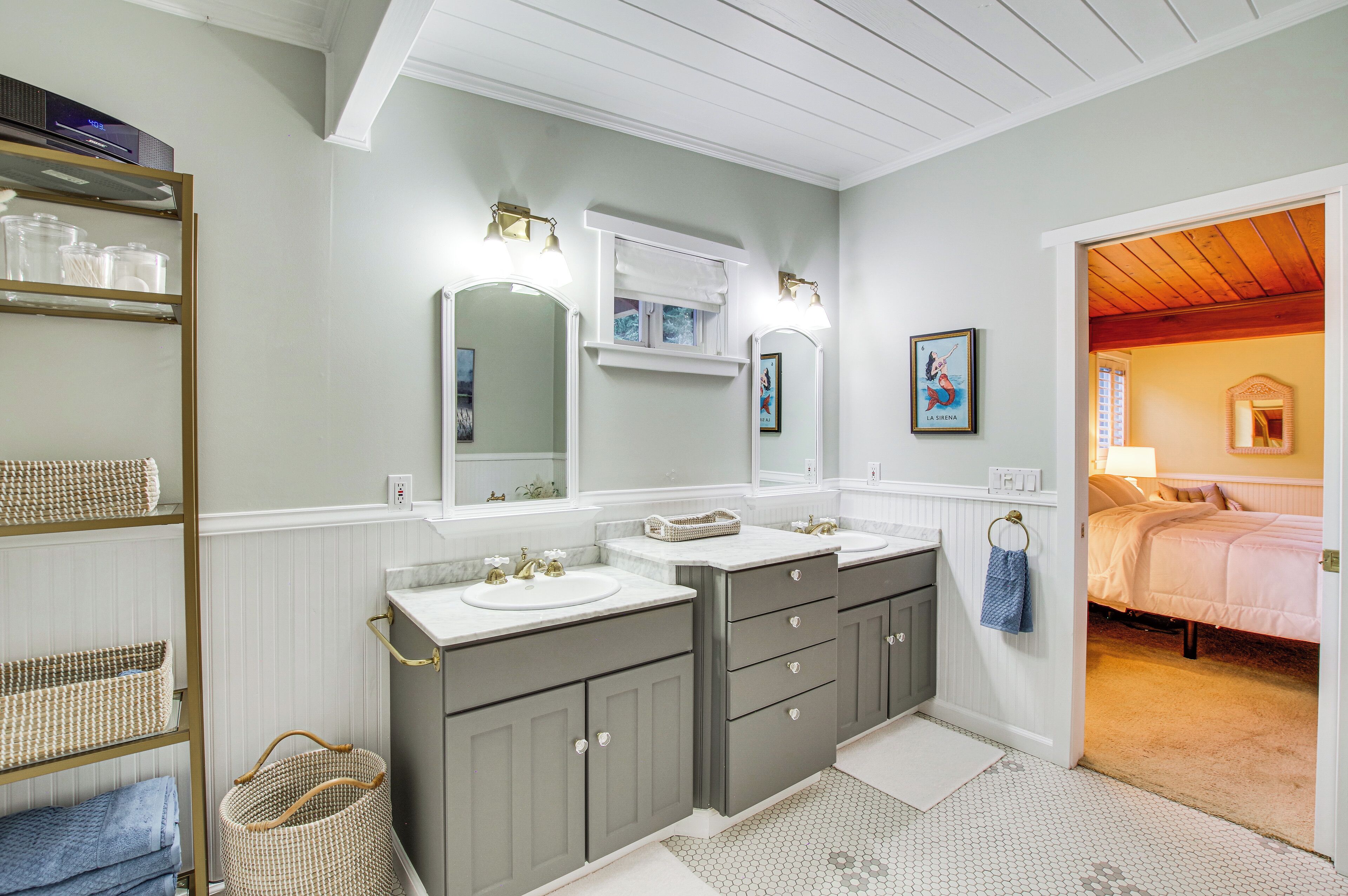 A bathroom with two sinks, a large mirror, and a wooden ceiling.