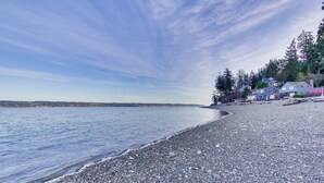 A pebble beach with houses and trees along the shore. - Puget Sound Cottage w/ Private Community Beach! (Coupeville)