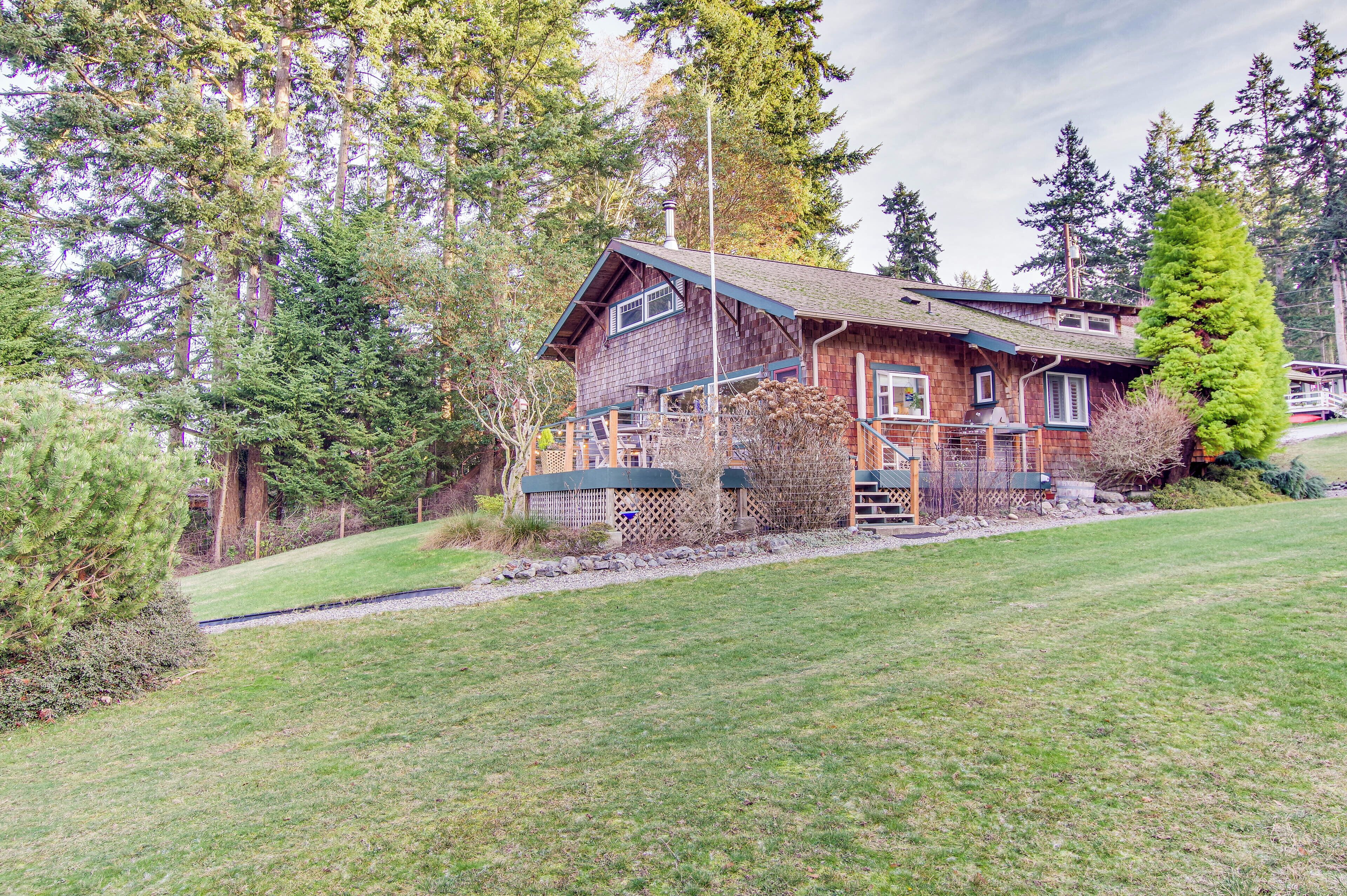 A rustic wooden cabin with a sloped roof, surrounded by dense forest.