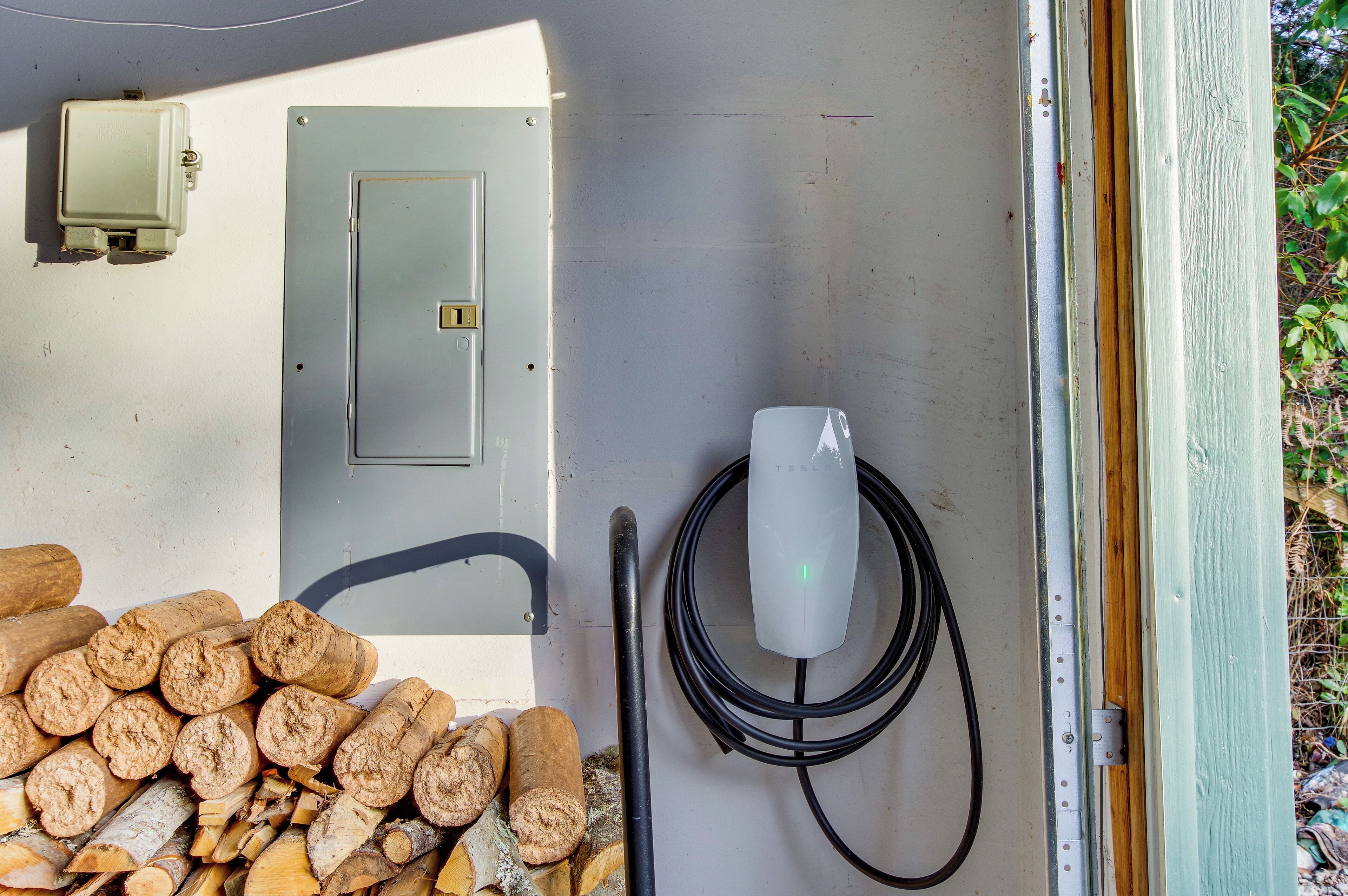 A utility box, a power outlet, and a coiled cable on a wall.