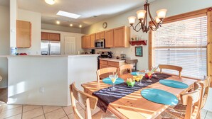 A kitchen with wooden cabinets, a refrigerator, and a dining area with a table set for four. - Lovely Albuquerque Home w/ Patio, 5 Mi to Old Town (Albuquerque)
