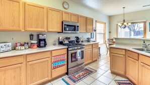 A kitchen with wooden cabinets, a microwave, a stove, and a coffee maker. - Lovely Albuquerque Home w/ Patio, 5 Mi to Old Town (Albuquerque)