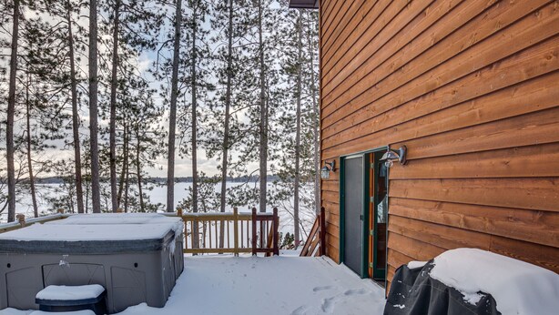 En stuga av trä med en veranda, ett bubbelbad och ett föremål som är täckt.