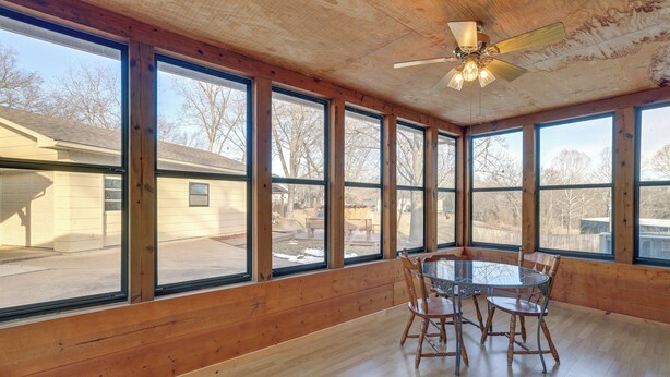 A spacious room with large windows, a ceiling fan, and a round glass table with chairs. - Pineville Home w/ Fire Pit < Half-mi to Elk River! (Pineville)