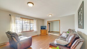 A spacious living room with a leather sofa, a wooden coffee table, and a television on a stand. - Pineville Home w/ Fire Pit < Half-mi to Elk River! (Pineville)