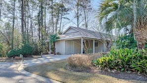A single-story house with a covered porch, surrounded by mature trees and a well-maintained lawn. - Northeast Wilmington Home ~ 5 Mi to Beach! (Wilmington)