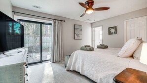 A bedroom with a large bed, a ceiling fan, a TV, and a sliding glass door leading to a balcony. - Northeast Wilmington Home ~ 5 Mi to Beach! (Wilmington)