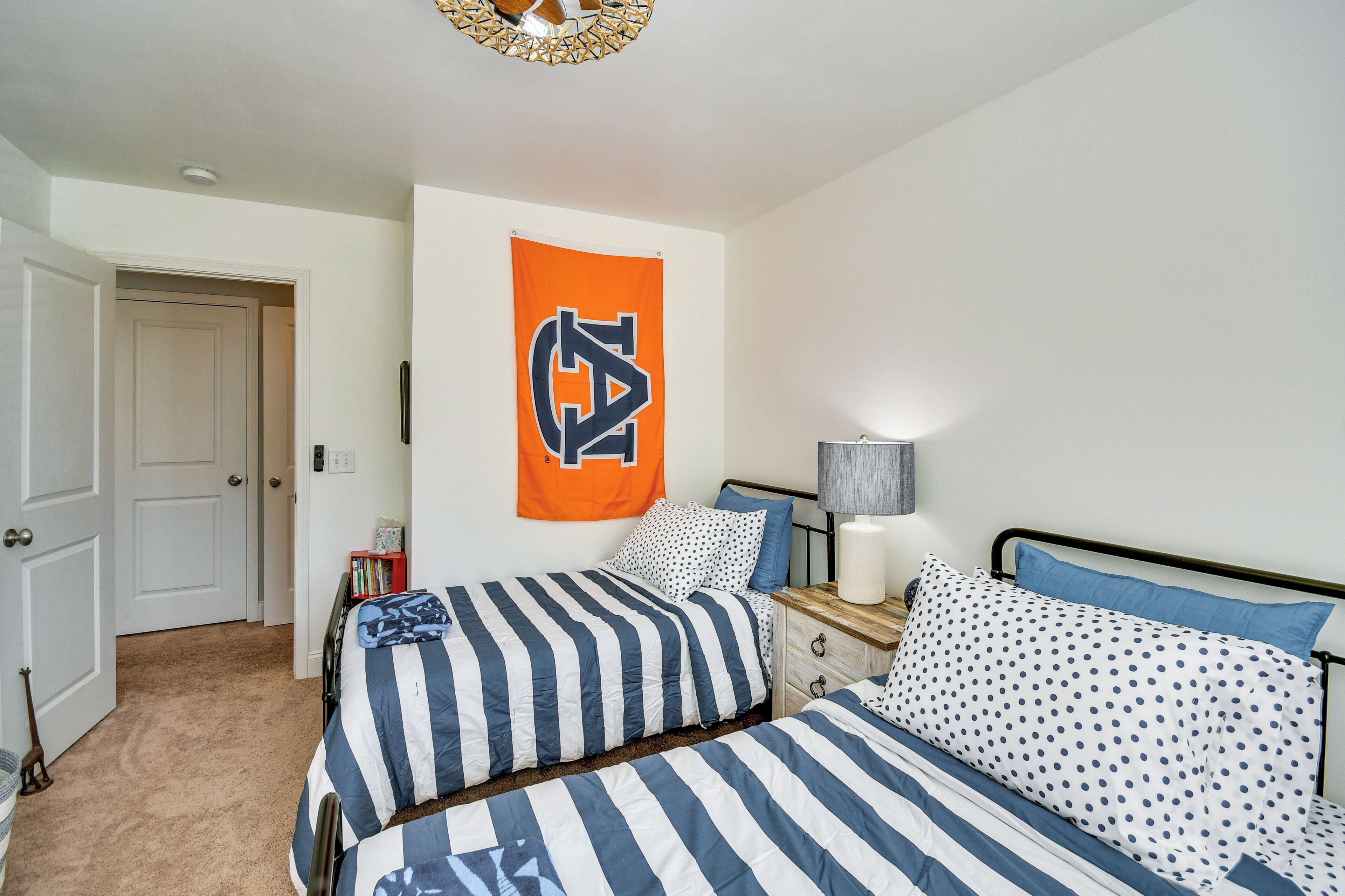 Ein Schlafzimmer mit zwei Betten, einem Nachttisch, einer Lampe und einer an der Wand hängenden Flagge.