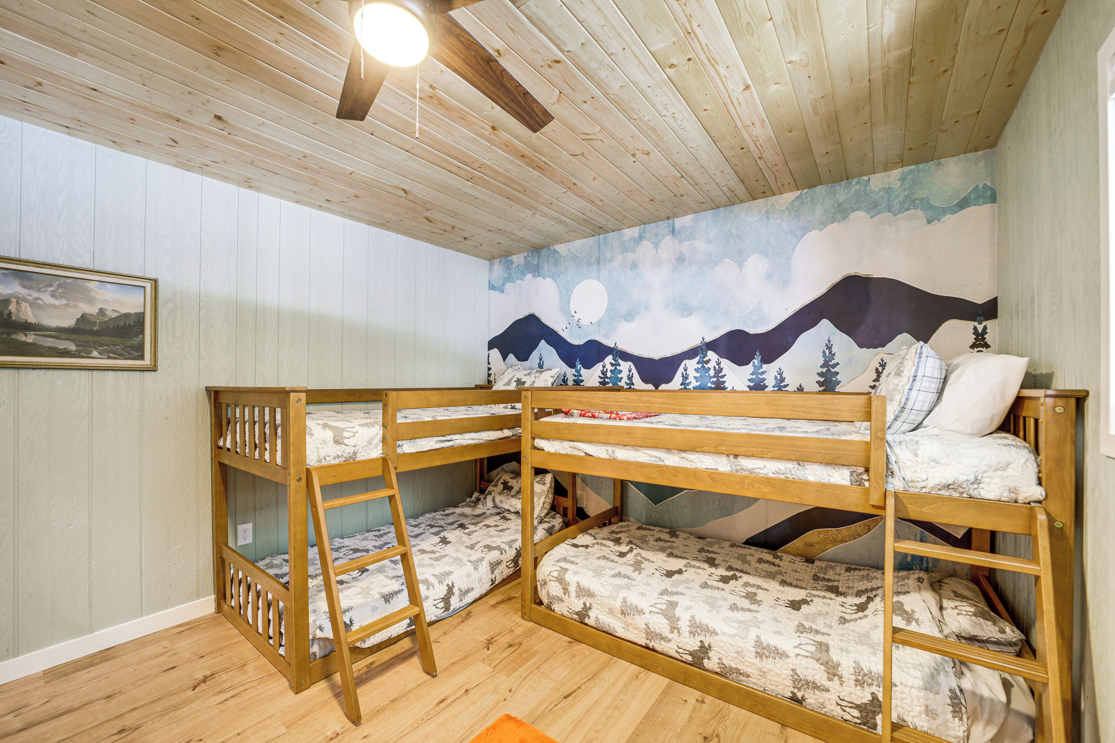 A bunk bed room with a wooden ceiling and a mural of mountains and a moon.