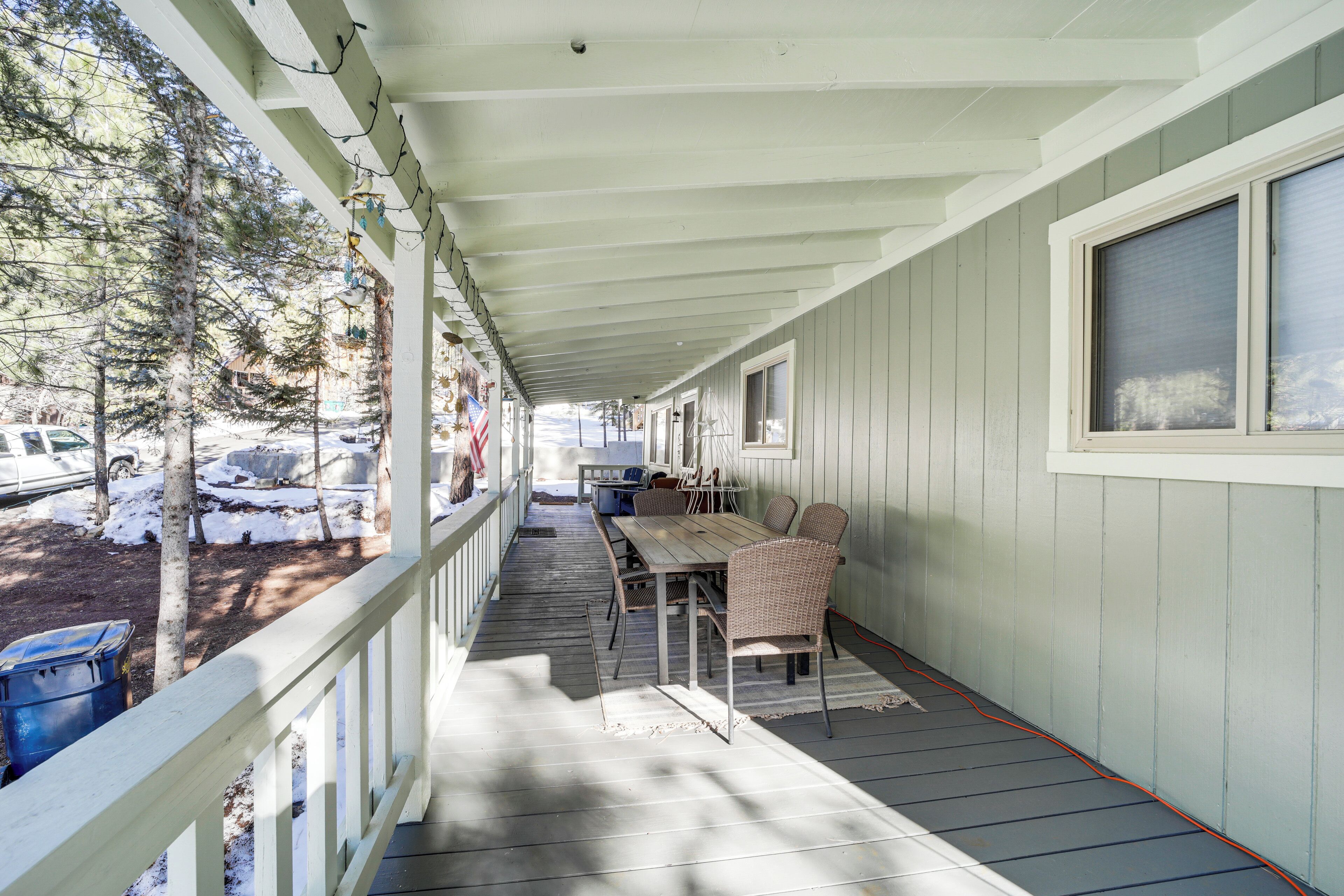 A covered porch with a table and chairs, a view of a snowy landscape, and a building in the background.
