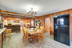 Una cocina con paneles de madera, una mesa de comedor, sillas y un refrigerador negro.