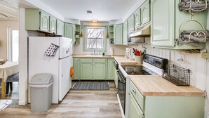 A compact kitchen with green cabinets, a white refrigerator, a stove, and a trash bin. - Riverfront Topsham Home ~ 28 Mi to Portland! (Topsham)