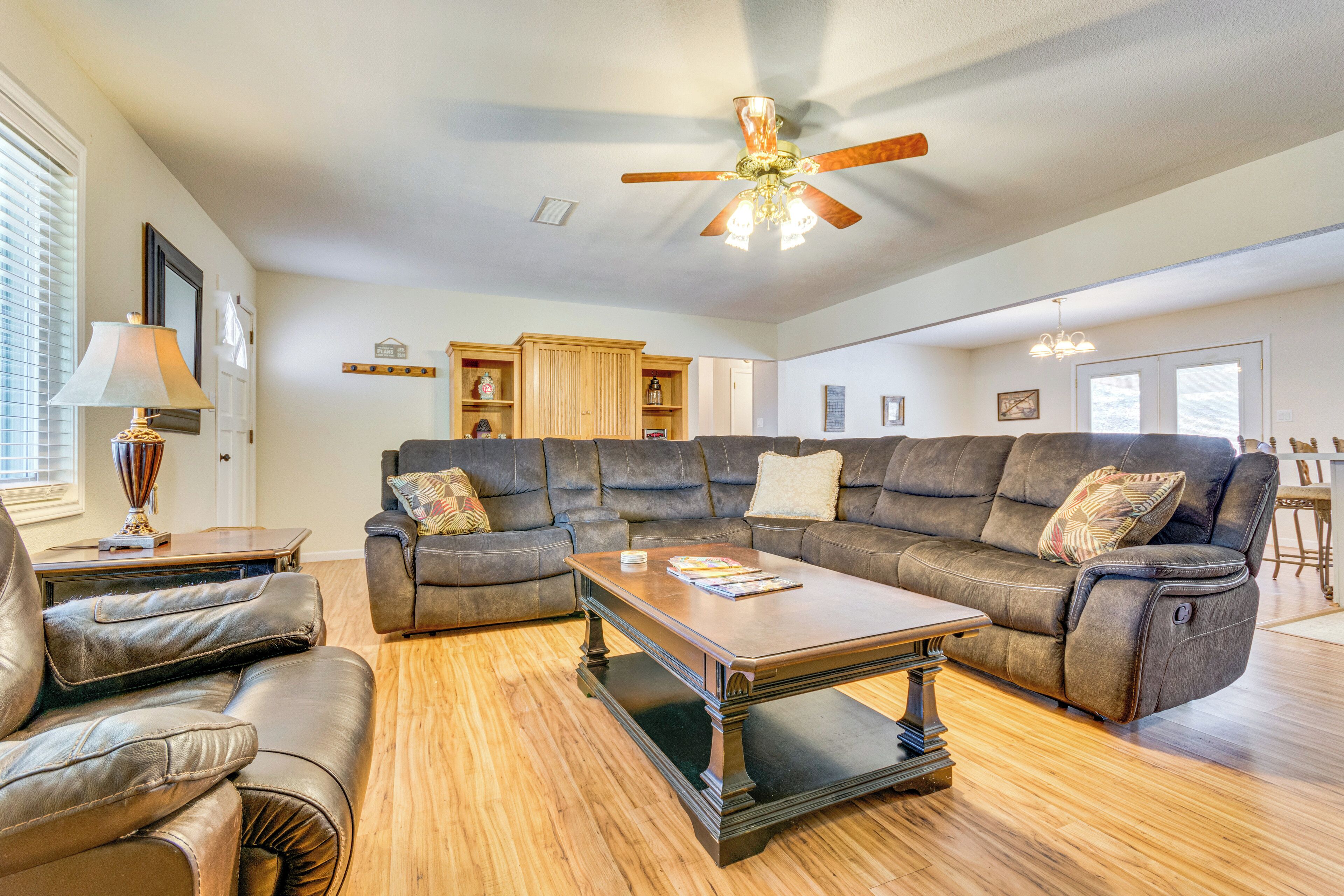 A spacious living room with a large sectional sofa, a coffee table, and a ceiling fan.