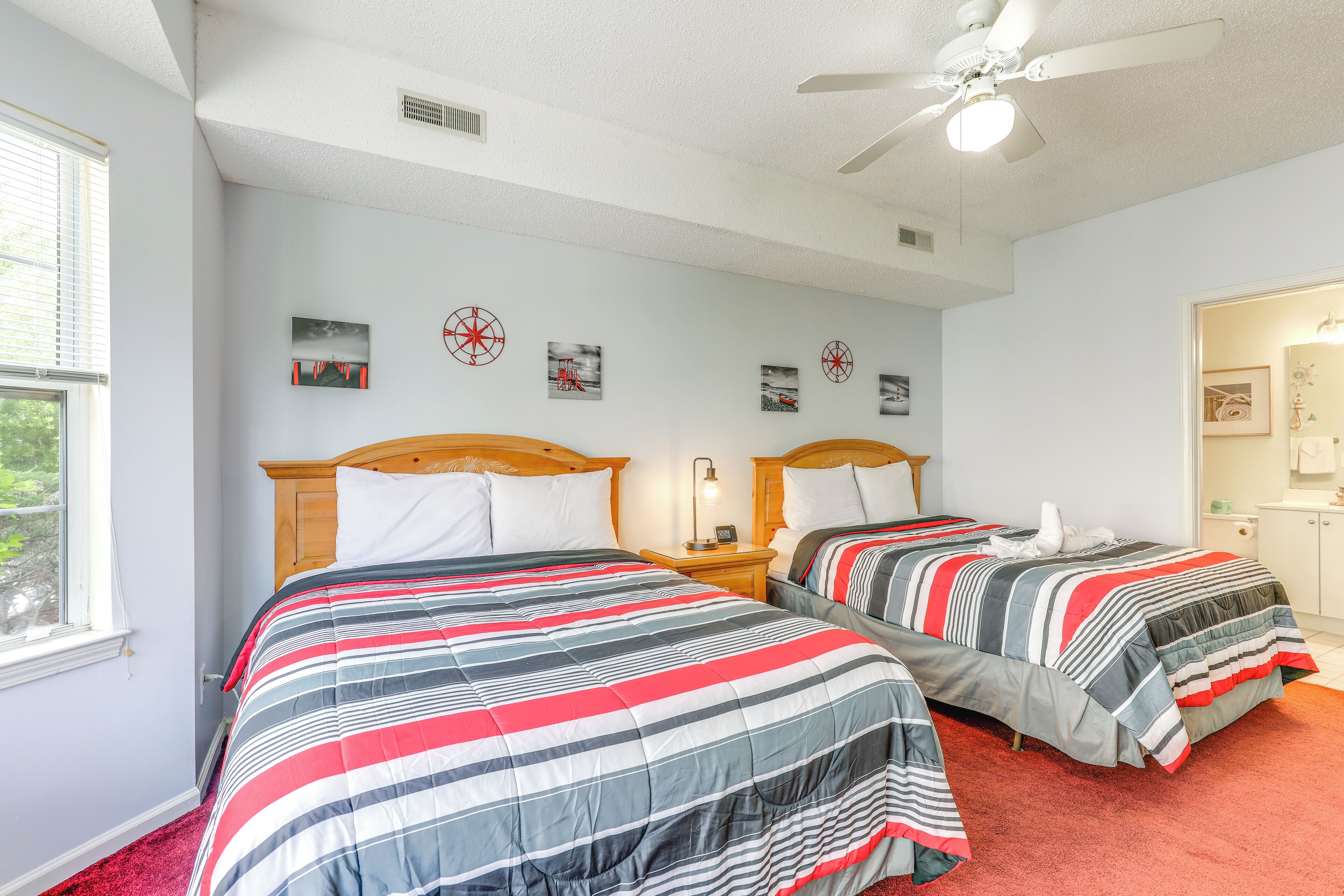 Une chambre avec deux lits, un ventilateur de plafond et une fenêtre.