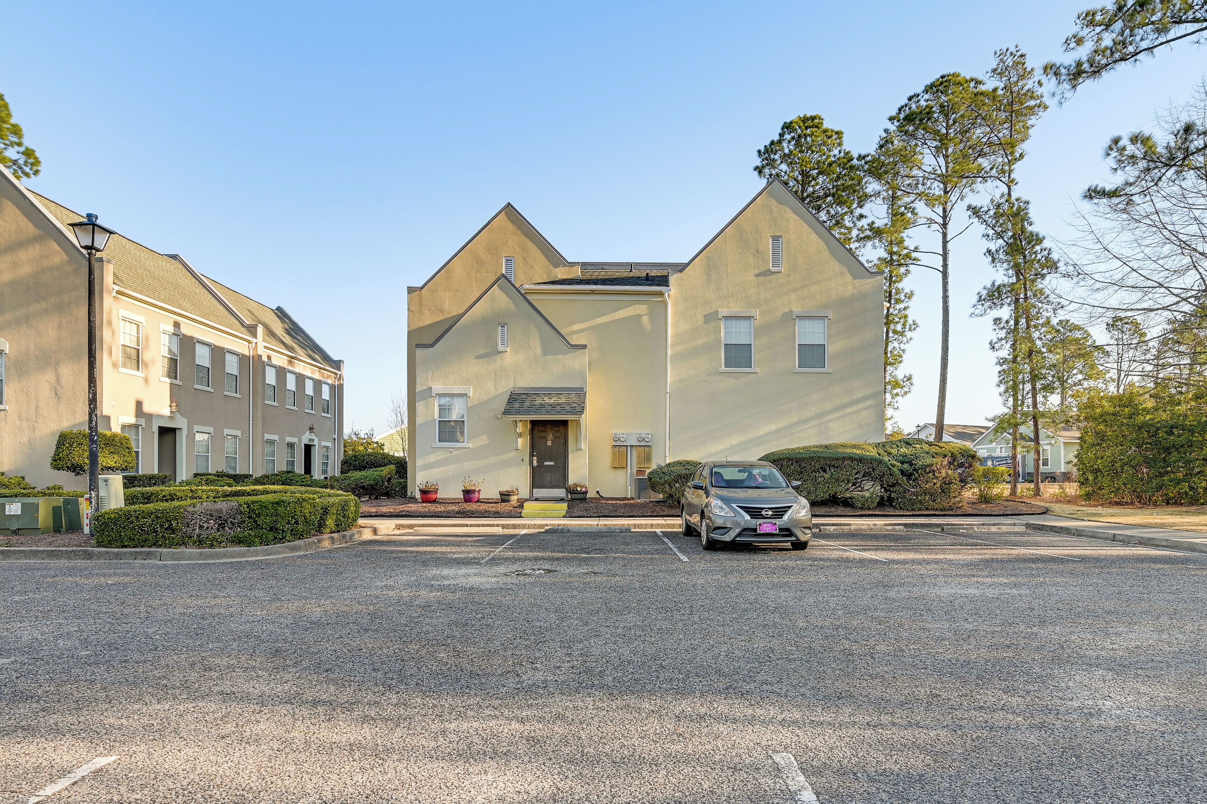 A residential building with a central entrance, a parking lot, and a car parked in front.