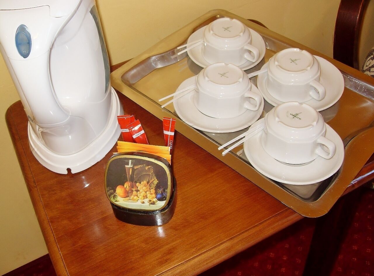 A safata amb quatre tasses i platets blancs, una tetera elèctrica blanca i un bol petit amb aliments sobre una taula de fusta.