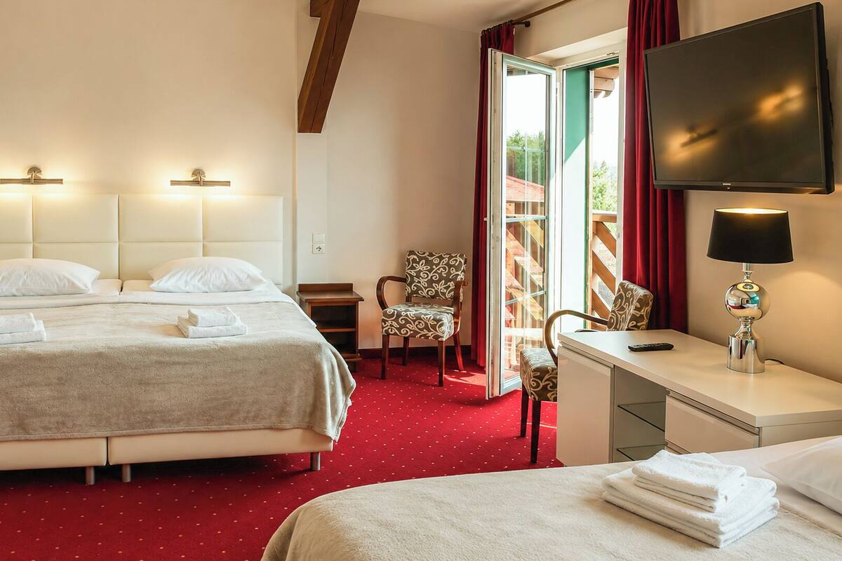 Una habitación de hotel con dos camas, un escritorio, una silla y un televisor.