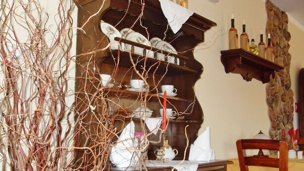 Un área de comedor con un armario de madera, una mesa con una silla y una pared decorativa con botellas y un detalle de piedra.