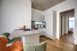 A modern kitchen with white cabinets, a countertop, and a dining area with chairs.